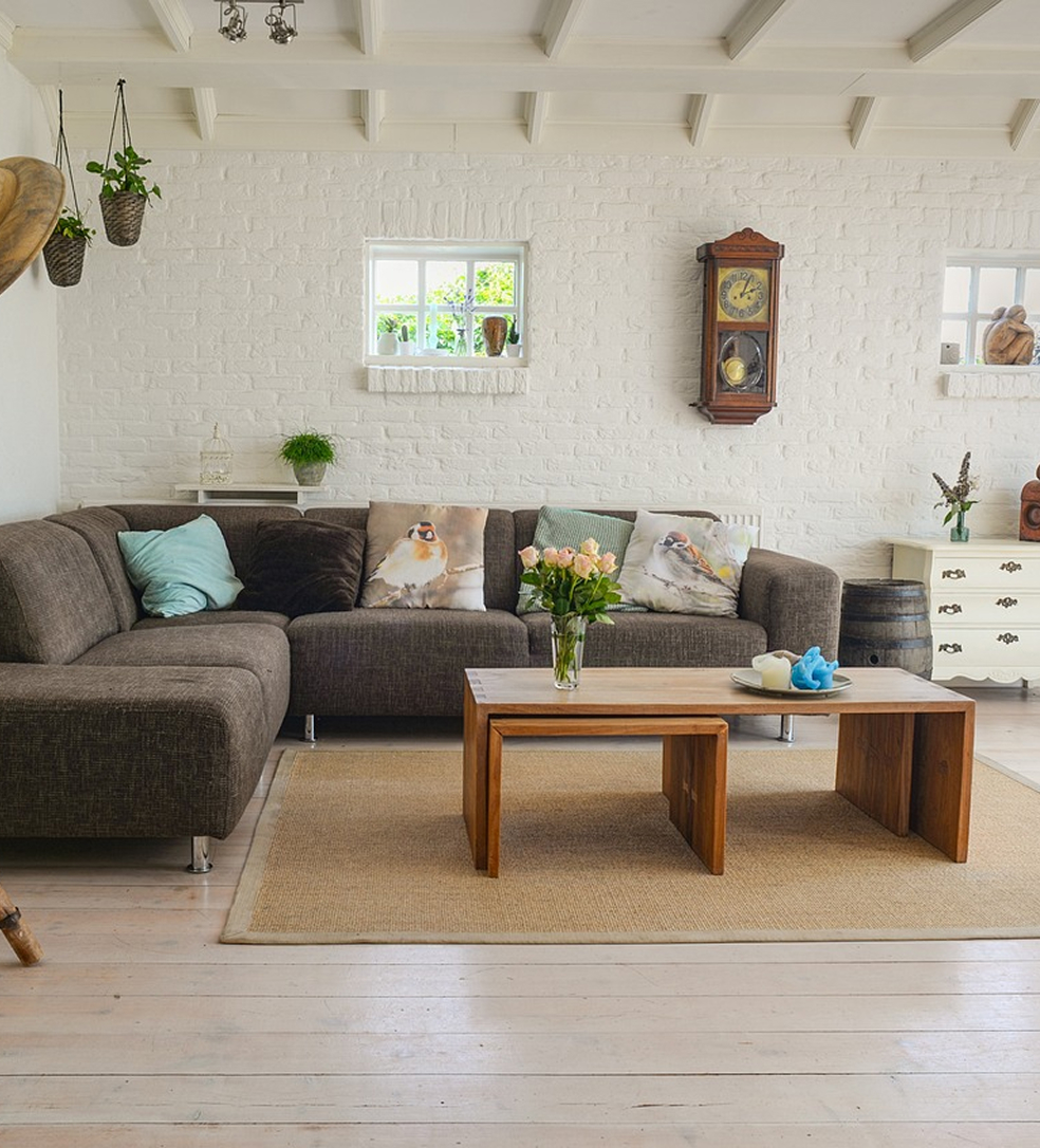 Sofá tapizado de diseño contemporáneo en salón neutro, acompañado de cojines decorativos y mesa de centro ligera — opción perfecta para crear un ambiente acogedor y elegante en la decoración del hogar.